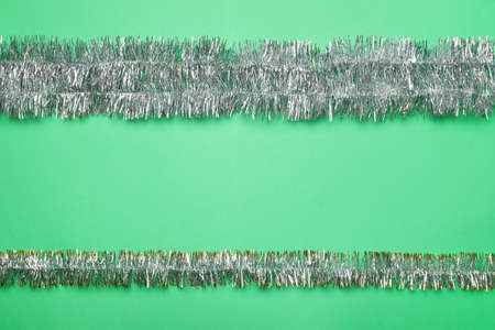 Silver tinsel on green background, flat lay. Space for textの写真素材