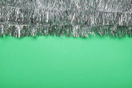 Silver tinsel on green background, top view. Space for textの写真素材