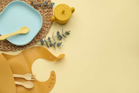 Flat lay composition with baby feeding accessories and bib on yellow background, space for textの写真素材