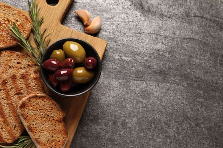 Tasty bruschettas, olives, rosemary and garlic on gray table, flat lay. Space for textの写真素材