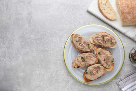 Slices of bread with delicious pate and microgreens on light gray table, flat lay. Space for text
