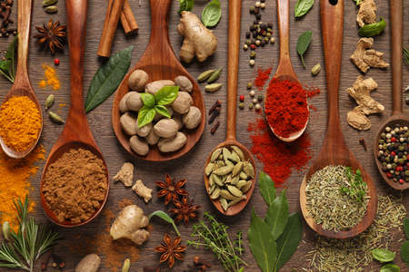 Different herbs and spices with spoons on wooden table, flat layの写真素材