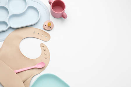 Composition with baby feeding accessories and bib on white background, top view. Space for textの写真素材