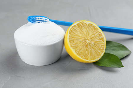 Toothbrush, lemon and bowl of baking soda on gray tableの写真素材