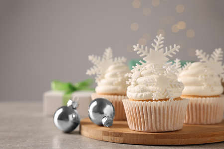 Tasty Christmas cupcakes with snowflakes on gray table. Space for textの写真素材
