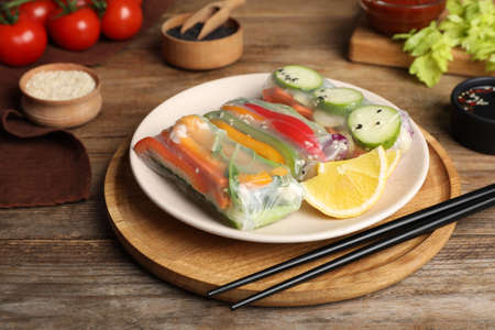 Delicious rolls wrapped in rice paper on wooden table