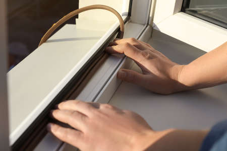 Construction worker putting sealing foam tape on window, closeup