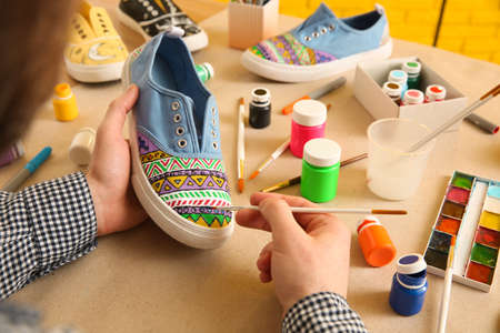 Man painting on sneaker at table, closeup. custom shoesの写真素材