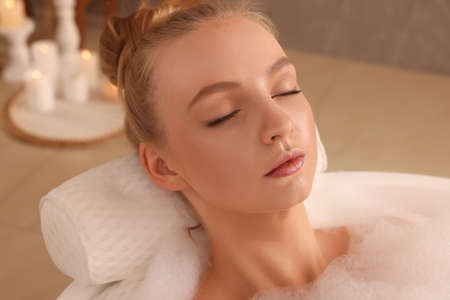 Young woman using pillow while enjoying bubble bath indoorsの写真素材