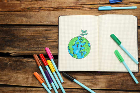 Happy Earth Day. Notebook with drawing of planet and markers on wooden table, flat layの写真素材