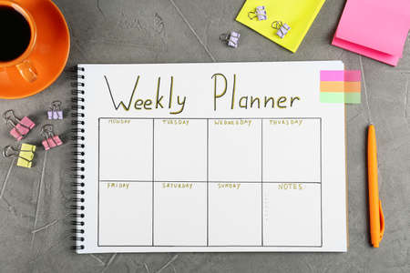 Flat lay composition of notebook with weekly plan on gray tableの写真素材
