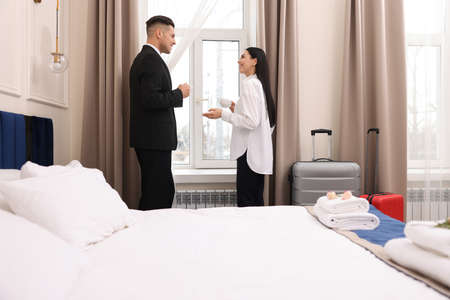 Businesspeople with cups of coffee near window in hotel room