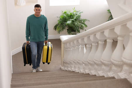 Handsome man with suitcases going up stairs in hotelの写真素材