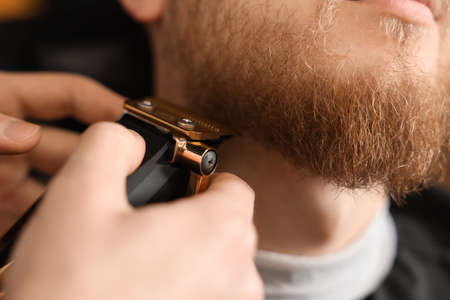 Professional hairdresser working with bearded client in barbershop, closeupの写真素材