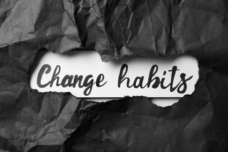 Text Change Habits on white background, view through hole in black torn paperの写真素材