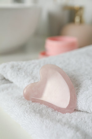 Rose quartz gua sha tool with soft towel on white table, closeupの写真素材