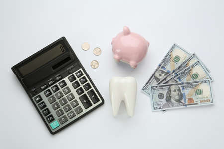 Flat lay composition with ceramic model of tooth and money on white background. Expensive treatmentの写真素材