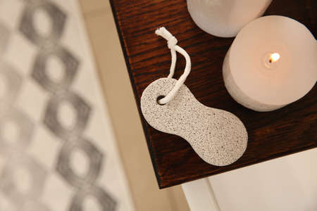 Pumice stone and burning candle on wooden caddy indoors, top view. Space for text