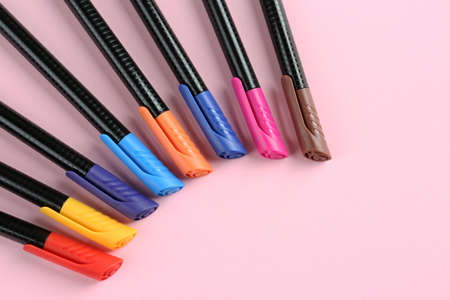 Many colorful markers on pink background, flat lay with space for text. school stationery