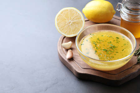 Bowl with lemon sauce and ingredients on dark table, space for text. Delicious salad dressingの写真素材