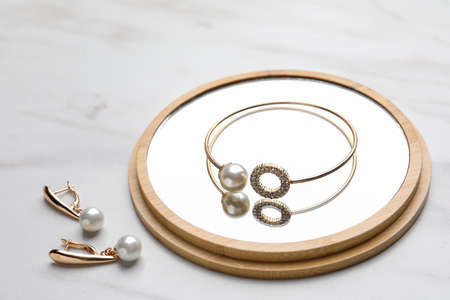Elegant bracelet and earrings with pearls on white marble tableの写真素材