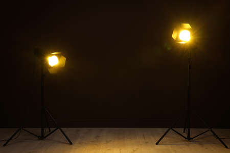 Bright spotlights near wall in dark room, space for text