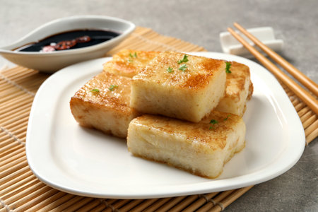 Plate with delicious turnip cake on gray tableの写真素材