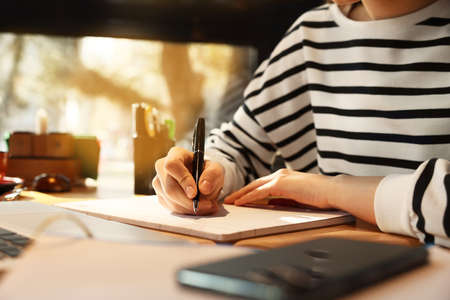 Young female student studying at table in cafe, closeup