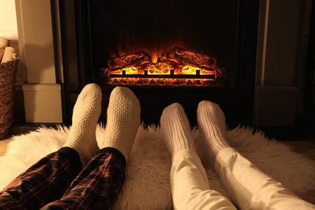 Couple in knitted socks near fireplace at home, closeup of legsの写真素材