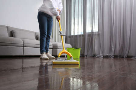 Woman cleaning parquet floor with mop indoors, closeup