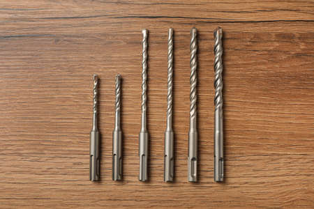 Different drill bits on wooden table, flat layの写真素材