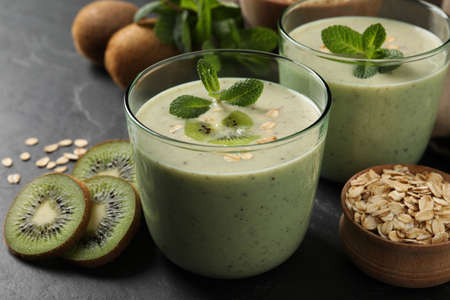 Glasses of tasty kiwi smoothie with oatmeal on dark tableの写真素材