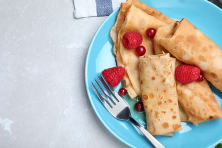 Delicious crepes served with berries on light gray table, top view. Space for textの写真素材