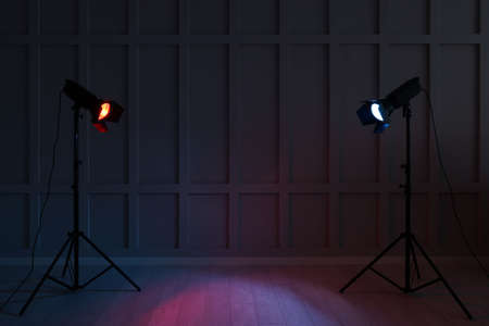 Bright red and blue spotlights near wall in dark room, space for textの写真素材
