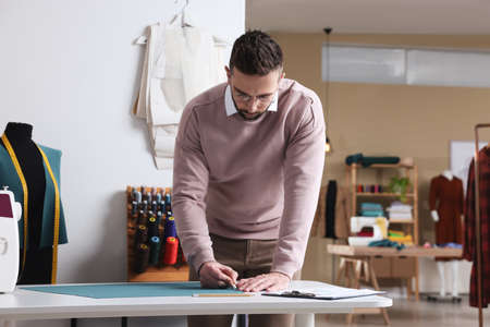 Dressmaker marking fabric with chalk in workshop