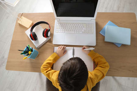 Cute little boy with modern laptop studying online at home, top view. e-learningの写真素材