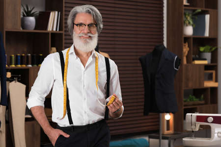 Professional tailor with measuring tape in workshop, space for text