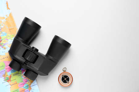 Modern binoculars, compass and world map on white background, flat lay. space for textの写真素材