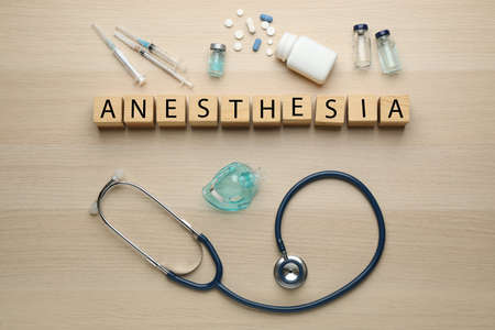 Word Anesthesia made of wooden cubes, stethoscope and drugs on table, flat layの写真素材
