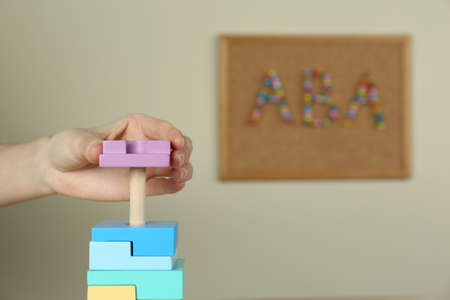 Child playing with toy pyramid indoors, closeup. ABA therapy conceptの写真素材