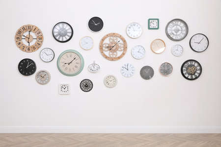 Collection of different clocks hanging on white wall in room