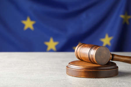 Wooden judge's gavel on gray table against European Union flag. Space for textの写真素材
