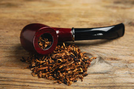 Smoking pipe with tobacco on wooden tableの写真素材
