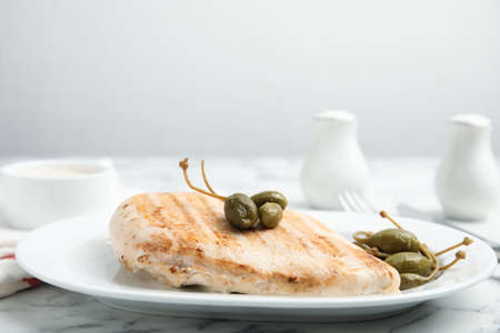Delicious cooked chicken fillet with capers served on white marble tableの写真素材