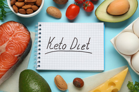 Notebook with phrase Keto Diet and different products on light blue background, flat layの写真素材
