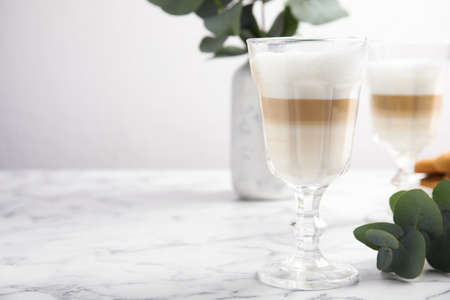 Delicious latte macchiato and eucalyptus branch on white marble table. Space for textの写真素材