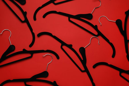 Empty clothes hangers on red background, flat layの写真素材