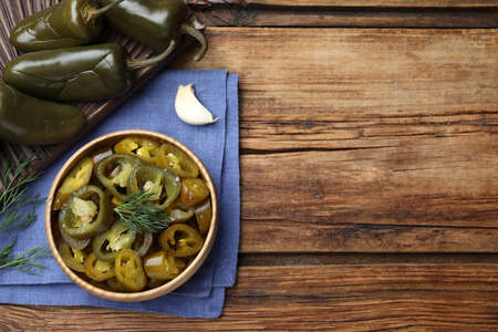 Flat lay composition with pickled green jalapeno peppers on wooden table, space for textの写真素材