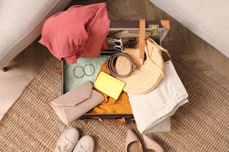 Open suitcase with different women clothes and accessories on carpet, top viewの写真素材