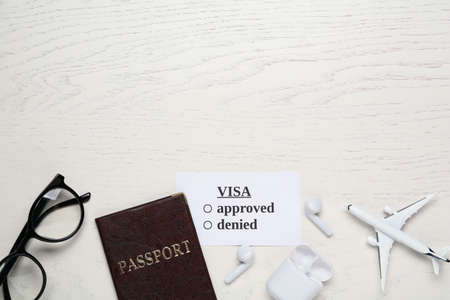 Flat lay composition with passport, toy plane and glasses on white wooden table, space for text.